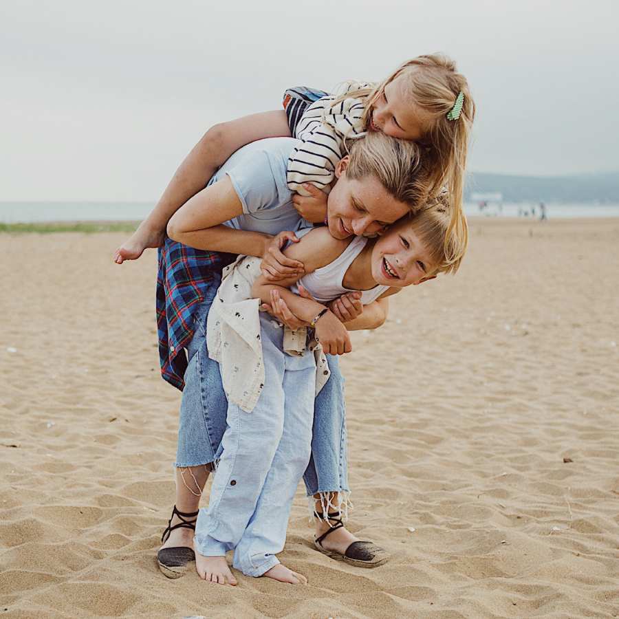 woman with 2 kids piled on her at the beach